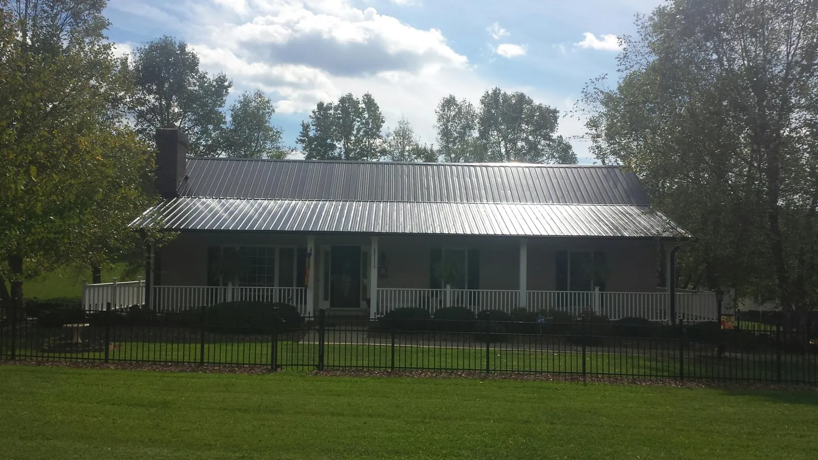 Gray metal roof on a brick ranch with a full width front porch — Gutter Guard Installation work by our crew in Redfield