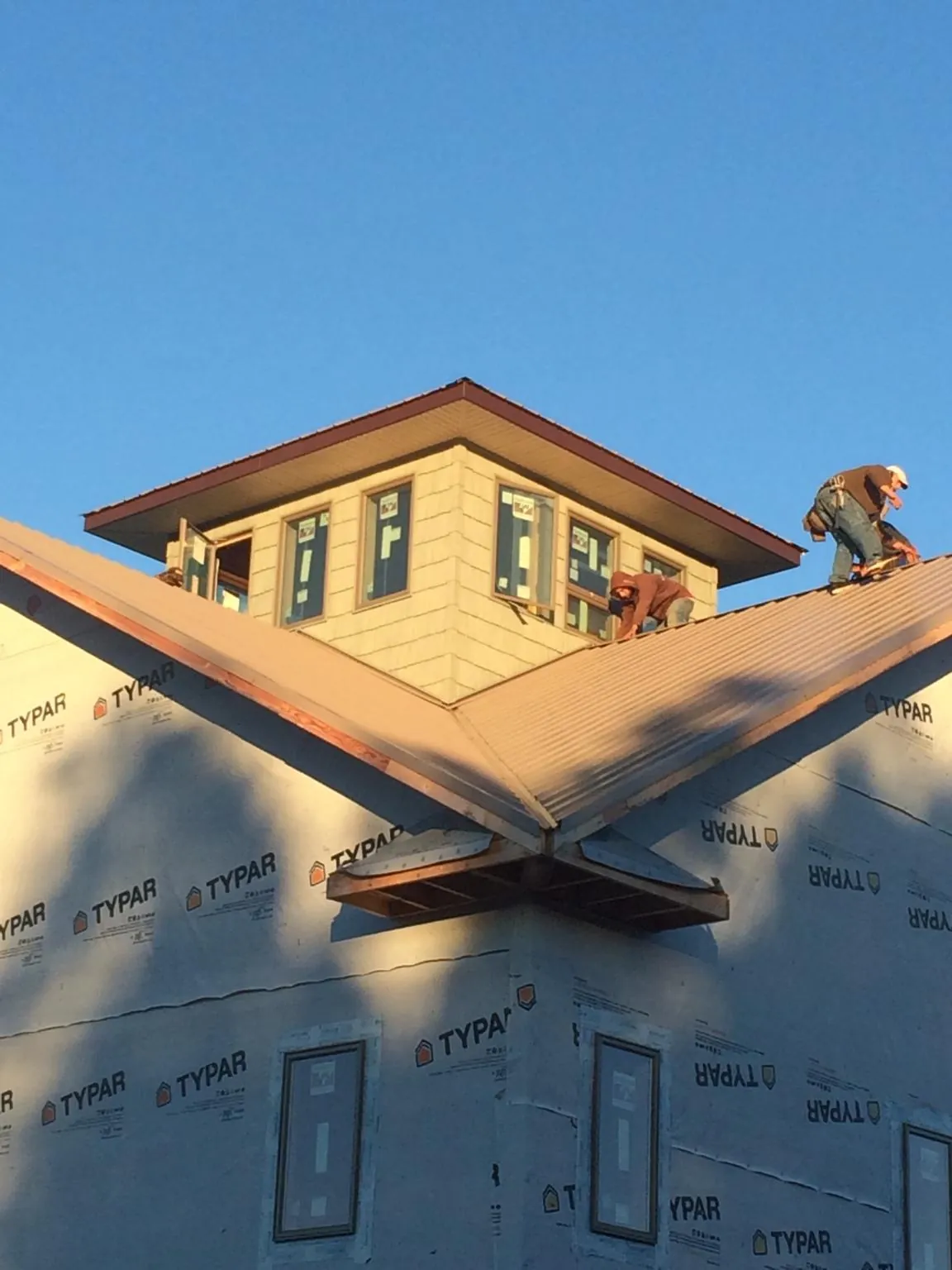 Roofers working around a rooftop cupola on a new metal roof at sunset — Roof Waterproofing in Redfield by Roofing Brothers